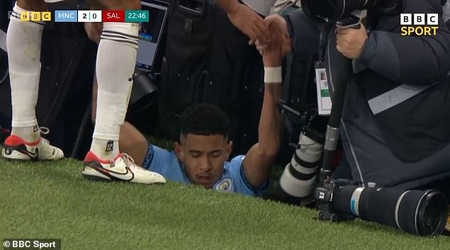 Manchester City star Savinho narrowly avoids injury after falling off the pitch into the photographer's pit following a collision with Salford's Curtis Tilt.